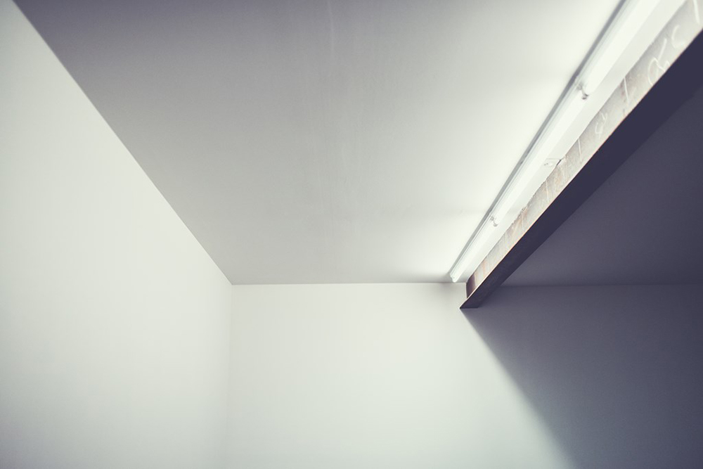 Un angle de la galerie : murs blancs, lumière rasante sous le plafond.